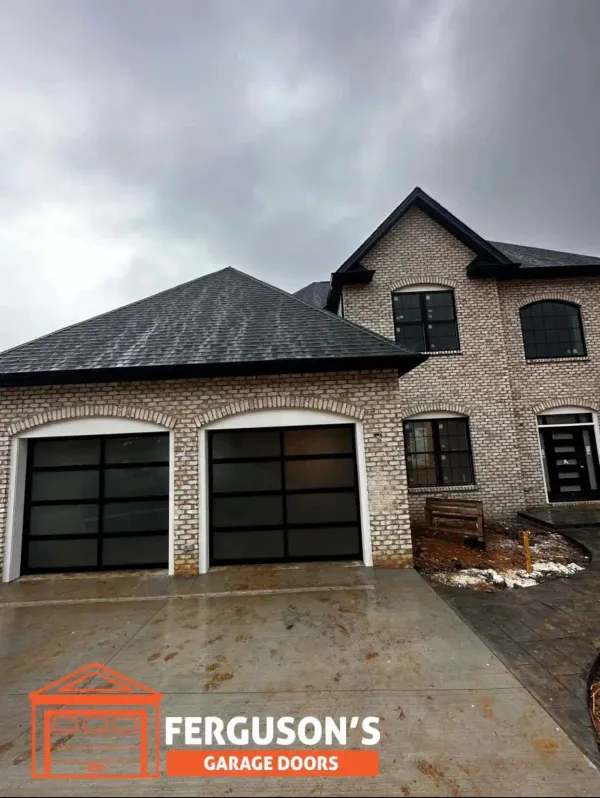 Modern aluminum and full-view glass panel garage doors on upscale brick home in Cave Spring