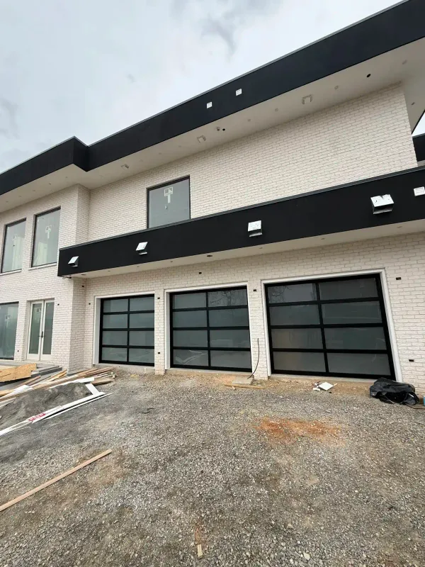 Three modern aluminum and glass garage doors on new-construction luxury home