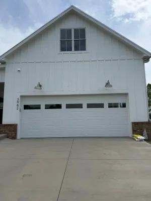 White long-panel garage door on board-and-batten farmhouse