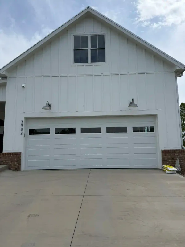 White long-panel garage door on board-and-batten farmhouse