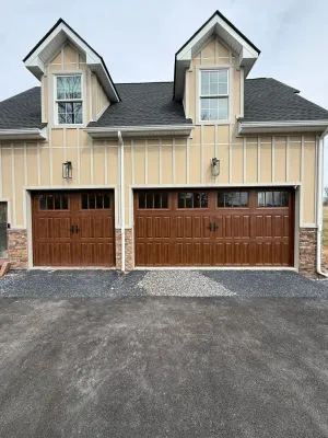 Luxury brown wood carriage garage doors with glass transom windows on Tudor-style home
